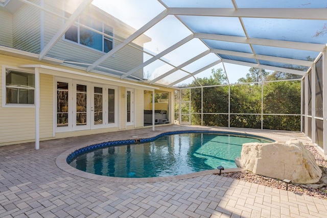 outdoor pool featuring a lanai, a patio area, and french doors