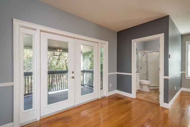 doorway with french doors, a healthy amount of sunlight, baseboards, and hardwood / wood-style flooring