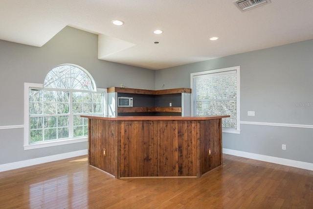 kitchen featuring visible vents, baseboards, white microwave, wood-type flooring, and recessed lighting