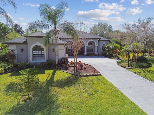 mediterranean / spanish home featuring stucco siding, roof with shingles, driveway, a front lawn, and a garage