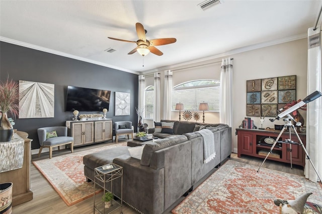 living room featuring wood-type flooring, ornamental molding, and ceiling fan