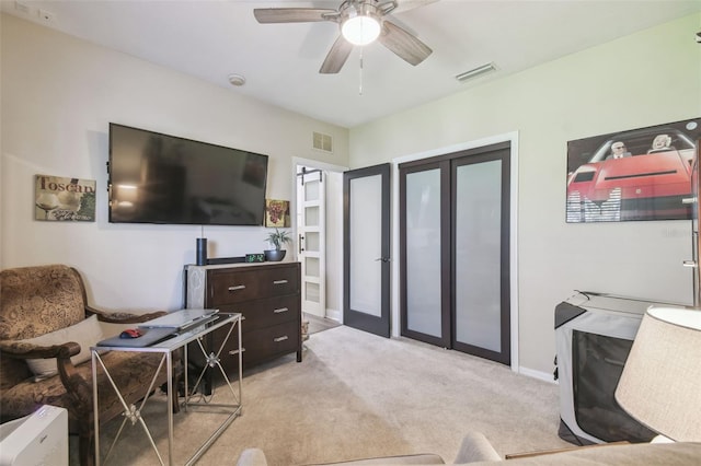 interior space with light carpet, french doors, and ceiling fan