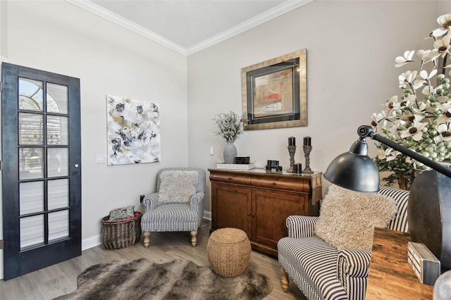 sitting room featuring baseboards, crown molding, and wood finished floors