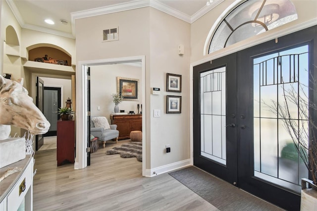 entryway with french doors, ornamental molding, baseboards, light wood finished floors, and visible vents