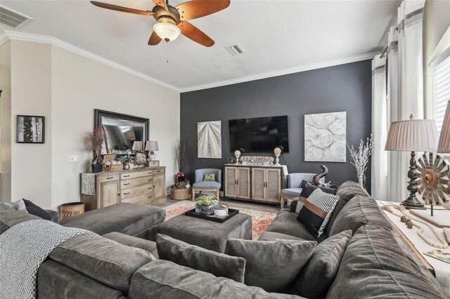 living area with crown molding, visible vents, and a ceiling fan