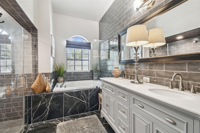 bathroom with double vanity, a sink, a stall shower, and tile walls