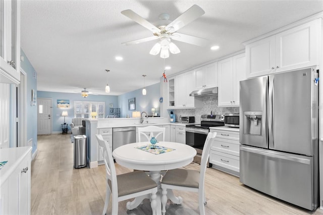 kitchen featuring appliances with stainless steel finishes, white cabinetry, hanging light fixtures, tasteful backsplash, and kitchen peninsula