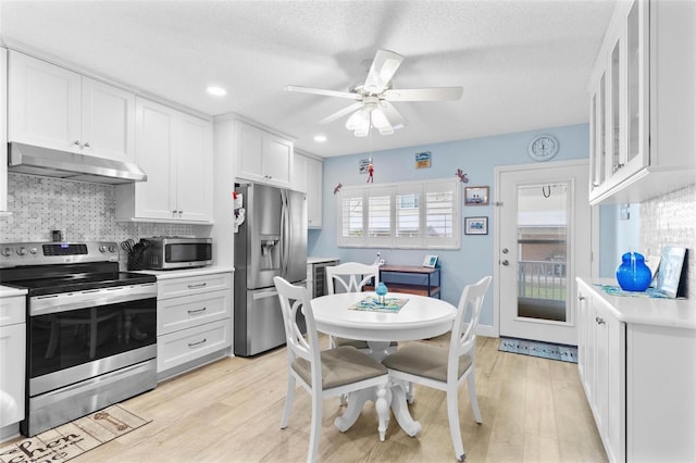 kitchen featuring white cabinetry, appliances with stainless steel finishes, light hardwood / wood-style floors, and backsplash