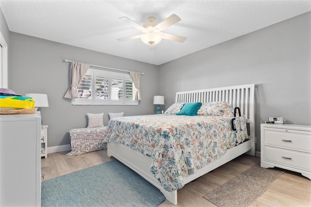 bedroom with ceiling fan, a textured ceiling, and light hardwood / wood-style flooring