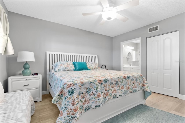 bedroom featuring ensuite bathroom, a closet, ceiling fan, and light wood-type flooring