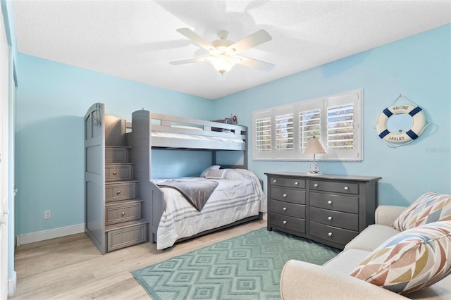 bedroom with ceiling fan, light hardwood / wood-style flooring, and a textured ceiling