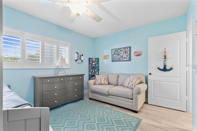 bedroom featuring ceiling fan, a textured ceiling, multiple windows, and light hardwood / wood-style flooring