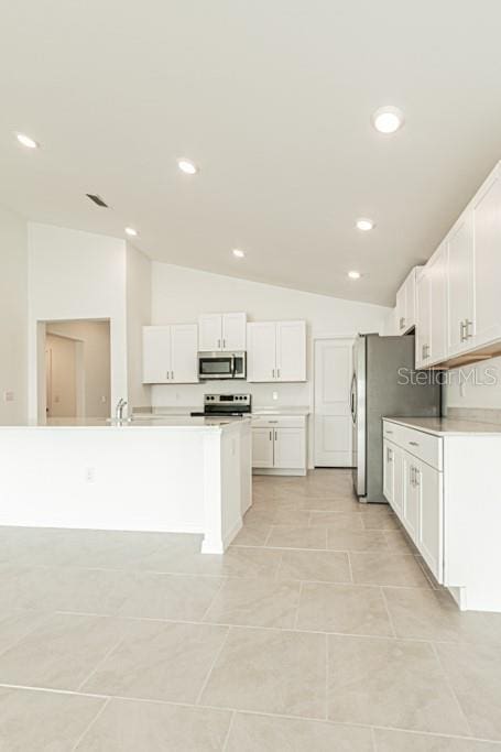 kitchen featuring stainless steel appliances, lofted ceiling, sink, and white cabinets