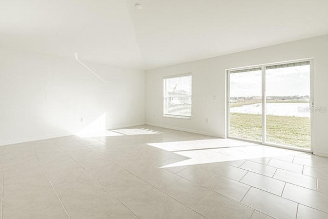 unfurnished room featuring a water view and light tile patterned floors