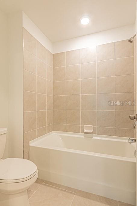 bathroom with tile patterned flooring, toilet, and shower / bathing tub combination