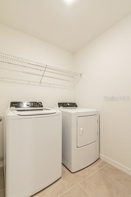 clothes washing area with separate washer and dryer and light tile patterned floors