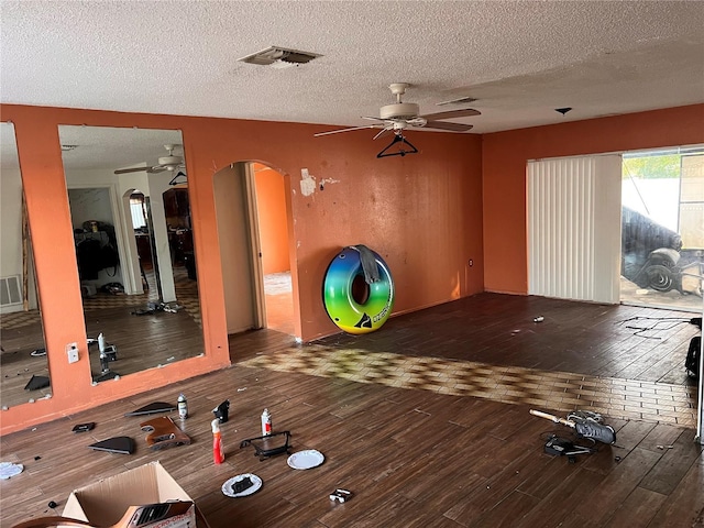 exercise room featuring ceiling fan, wood-type flooring, and a textured ceiling