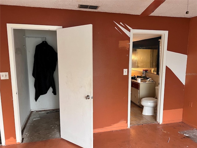 bedroom featuring connected bathroom and a textured ceiling