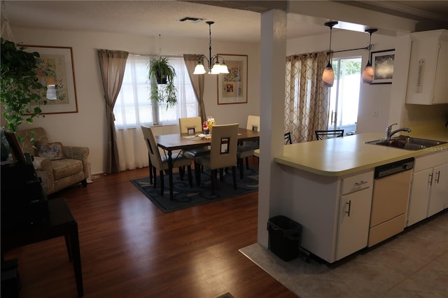 kitchen with hanging light fixtures, dishwasher, sink, and white cabinets