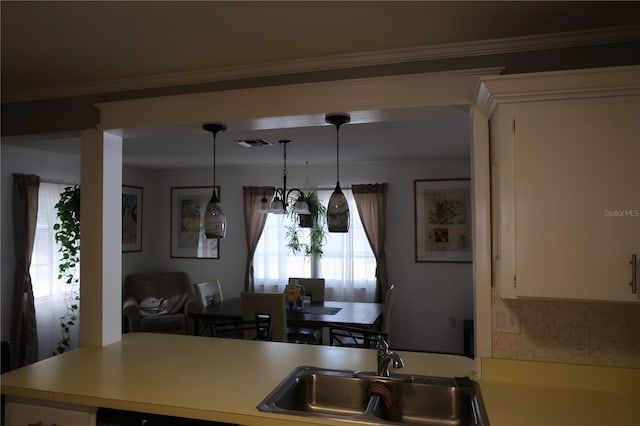 kitchen with hanging light fixtures, sink, and white cabinets