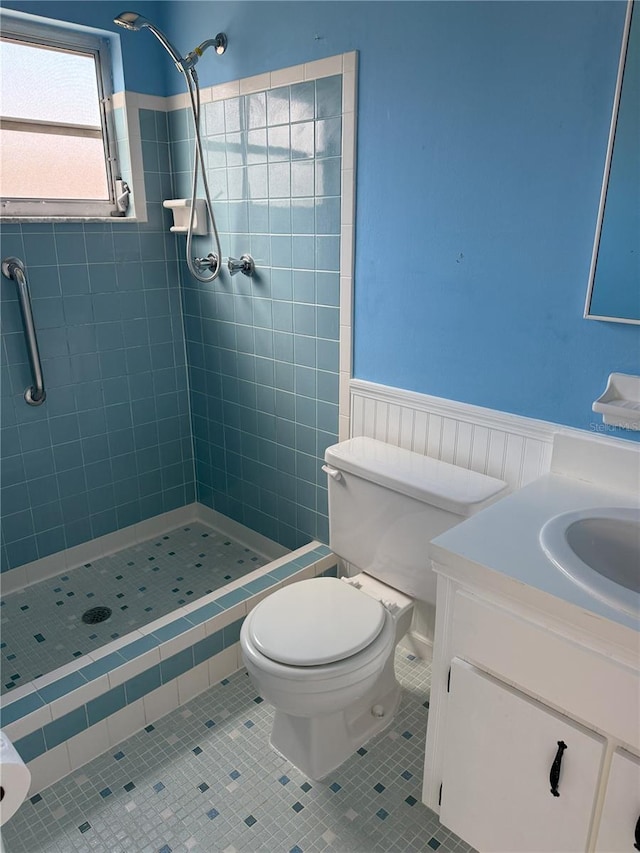 bathroom with tiled shower, vanity, toilet, and tile patterned flooring