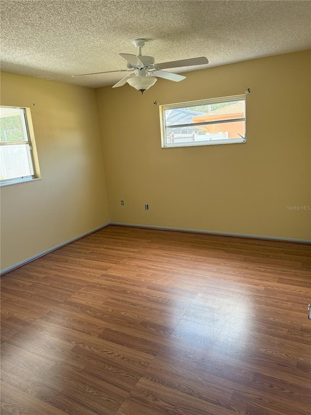 spare room featuring hardwood / wood-style floors, a wealth of natural light, and a textured ceiling