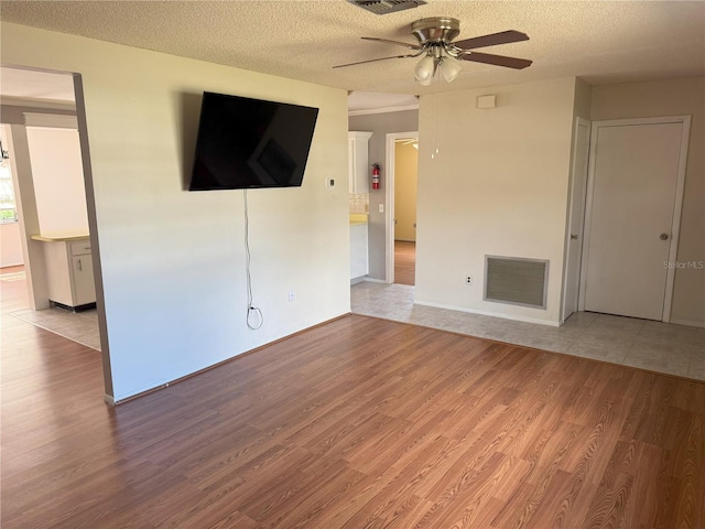 unfurnished living room with ceiling fan, light hardwood / wood-style flooring, and a textured ceiling