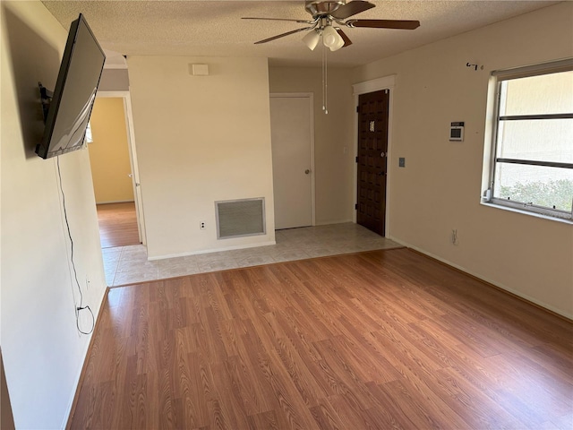 unfurnished living room with ceiling fan, a textured ceiling, and light wood-type flooring