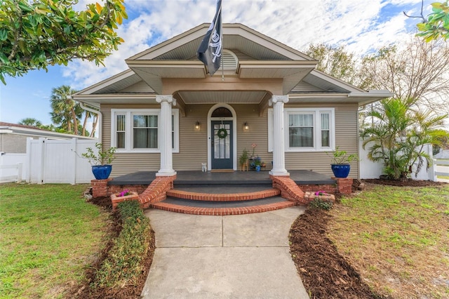 bungalow-style house featuring covered porch, a gate, fence, and a front yard