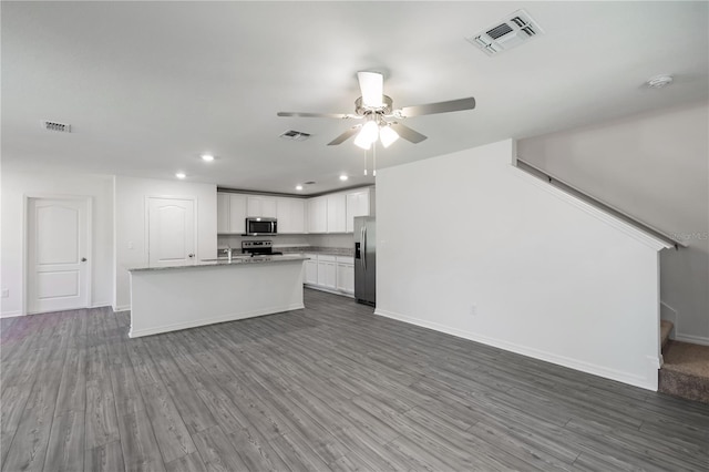 kitchen featuring white cabinets, a kitchen island with sink, ceiling fan, stainless steel appliances, and dark wood-type flooring