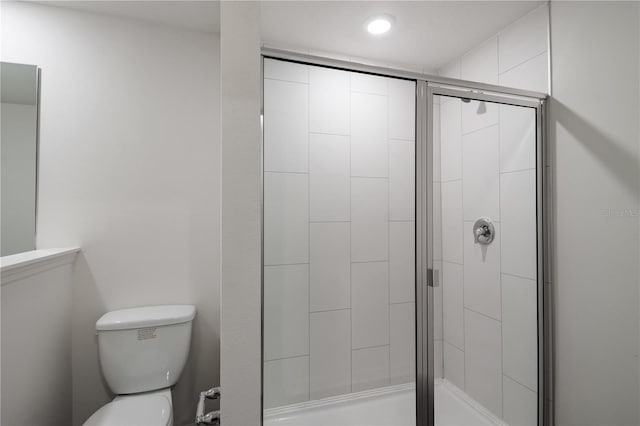 bathroom featuring a shower with shower door and toilet