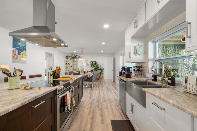 kitchen featuring white cabinetry, island exhaust hood, stainless steel appliances, and light stone countertops