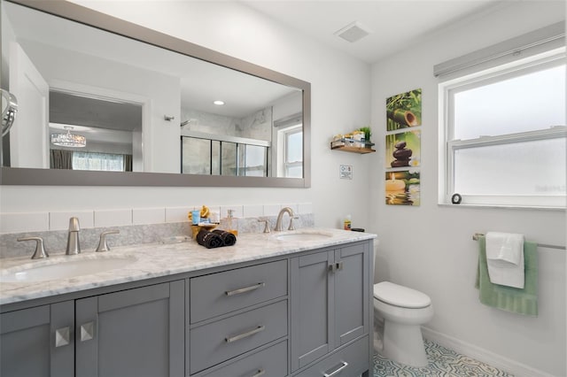 bathroom featuring an enclosed shower, vanity, toilet, and a healthy amount of sunlight