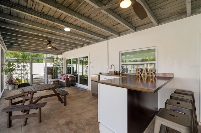 interior space with sink, wood ceiling, kitchen peninsula, beamed ceiling, and ceiling fan