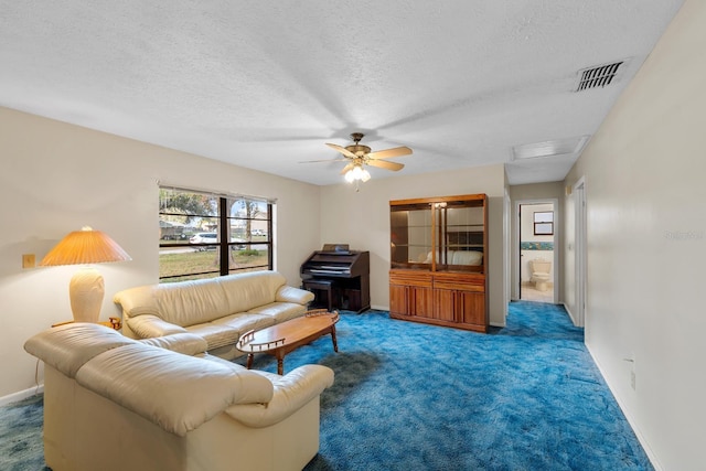 carpeted living room featuring ceiling fan and a textured ceiling