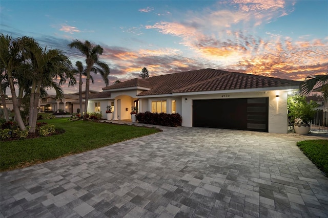 mediterranean / spanish house with a garage and a lawn