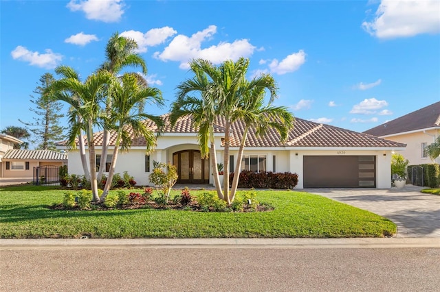 mediterranean / spanish home featuring a garage and a front lawn