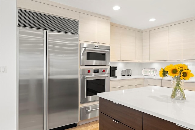 kitchen with dark brown cabinetry, appliances with stainless steel finishes, and cream cabinets