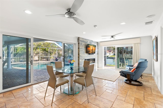 dining space featuring ceiling fan, a healthy amount of sunlight, and a fireplace