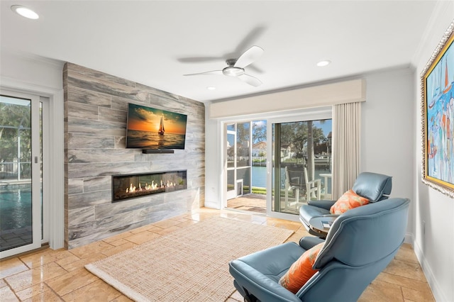 interior space featuring a tiled fireplace, ornamental molding, a wealth of natural light, and ceiling fan