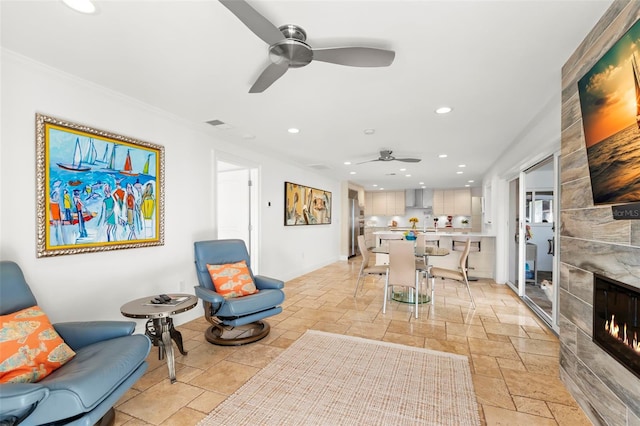 living room with a tiled fireplace and ceiling fan