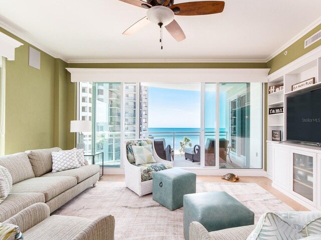 living room with plenty of natural light, ornamental molding, a ceiling fan, and visible vents