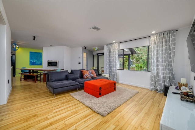 living room featuring light wood-type flooring, visible vents, baseboards, and recessed lighting