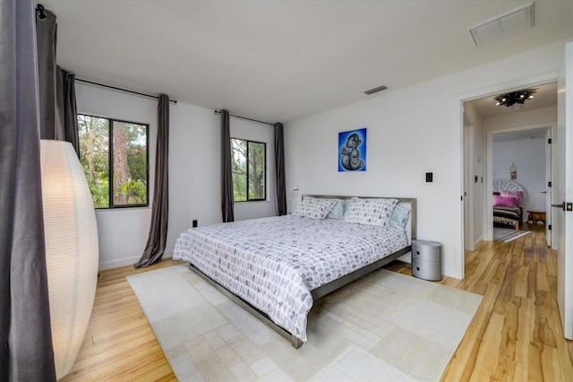 bedroom featuring visible vents, baseboards, and wood finished floors