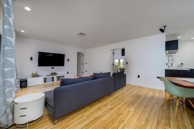 living room with recessed lighting, visible vents, light wood-style flooring, and baseboards