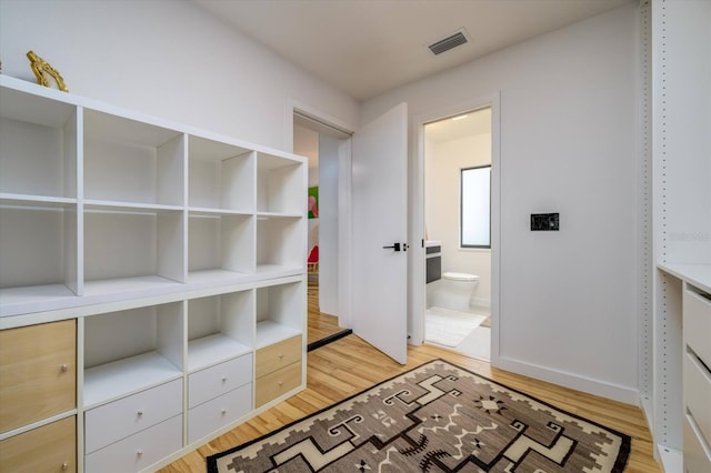 corridor featuring light wood finished floors, visible vents, and baseboards