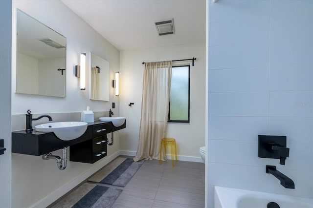 bathroom featuring visible vents, a sink, toilet, and a tub