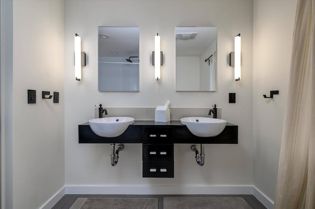 bathroom with visible vents, a sink, and baseboards