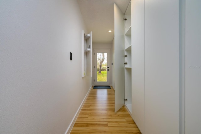 hall featuring light wood-style flooring and baseboards