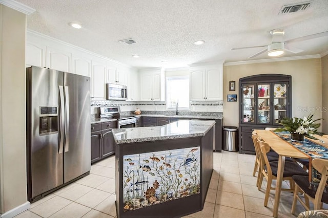 kitchen with sink, light tile patterned floors, stainless steel appliances, light stone countertops, and white cabinets